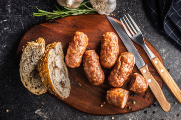 Photo of roasted italian sausage salsiccia on cutting board on black table.