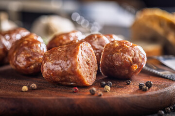Photo of roasted italian sausage salsiccia on cutting board on black table.