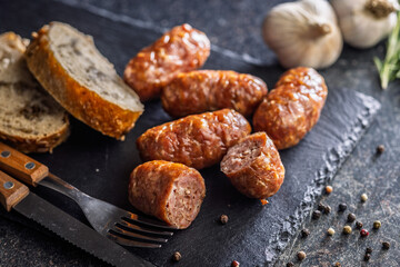Photo of roasted italian sausage salsiccia on cutting board on black table.