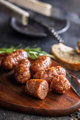 Photo of roasted italian sausage salsiccia on cutting board on black table.