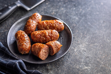Photo of roasted italian sausage salsiccia on plate on black table.