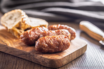 Photo of roasted italian sausage salsiccia on cutting board on wooden table.