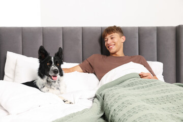 Pet friendly hotel. Man and his cute dog in bed indoors