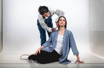 A stylist and make-up artist girl getting a beautiful and young brunette model ready for a photoshoot