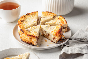 Homemade cottage cheese casserole pie with raisins. Baked cheesecake for healthy breakfast on white table background