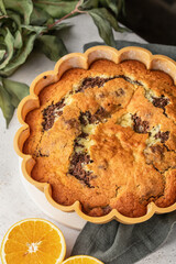 Orange and chocolate marble bundt cake in baking form. Fruity citrus dessert on light gray kitchen background