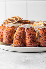 Orange and chocolate marble bundt cake with sugar icing close up. Fruity citrus dessert on light gray kitchen background