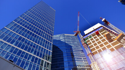 Crane on the construction site in a site surrounded by the high buildings. Office building under construction in the vicinity of high apartment buildings and office building.