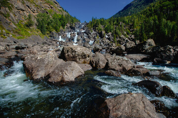 Scenic mountain waterfall flowing over rocks in lush forest valley