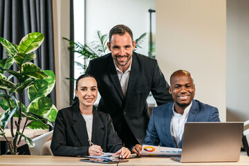 Group of diverse business professionals collaborating in a modern office space, showcasing teamwork and creativity with laptops and documents on a stylish wooden table