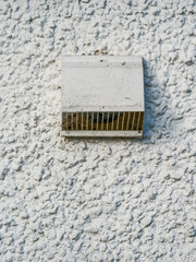 A white vent is on a wall of a house of office with a white background. The vent is dirty and has a lot of dust on it. Ventilation device for dirty air circulation