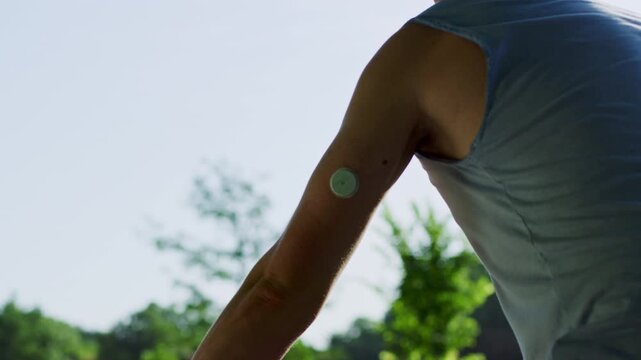 Shot of a cyclist with a diabetes monitor on his arm riding through a park on a sunny day.