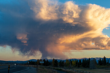 Cumulonimbus cloud illuminated by sunrise colors over Teton Valley, near Moose, Wyoming.  cloud formation exhibits shades of orange and pink against a blue sky over the Teton Park road        