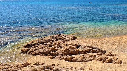 Blue expanse of the southern sea and rocky shoal on the sandy shore