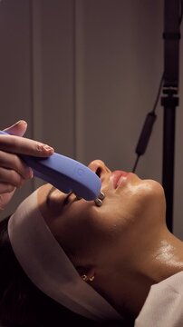 woman is receiving a microcurrent facial, a non-invasive skincare treatment. This procedure stimulates facial muscles for rejuvenation and anti-aging