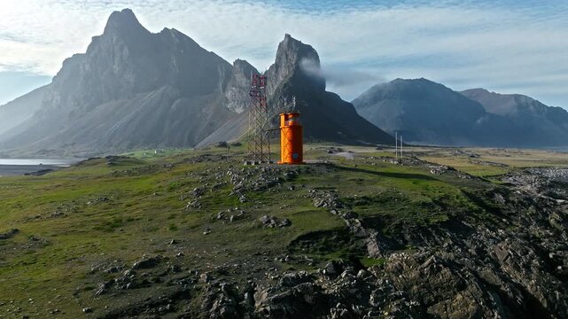 Hvalnes lighthouse and landscape Iceland. Drone shows orange tower standing isolated among cliffs and wild coastline.