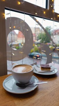 Latte placed on table near tall window with busy street outside and decorative round decal