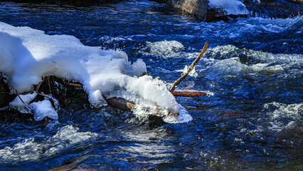Watercourse in the Pyrenees Orientales mountains in France. Fir forest, rock and tree trunk under the snow.
