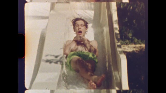 Fourteen year old boy riding down a white water slide with joyful expression in a sunny vintage setting