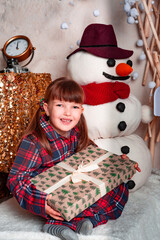 Happy little girl child in pajamas lies in bed with gifts of toys in bedroom. Christmas. New Year. St. Nicholas Day. Time of holidays and miracles.	