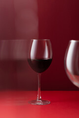 Still life of red wine glass on a deep red background with soft reflections