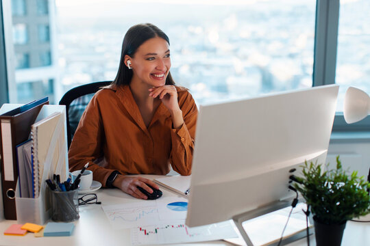 Entrepreneurship and management. Happy successful businesswoman working at workspace in office, lady with earbuds using computer for work