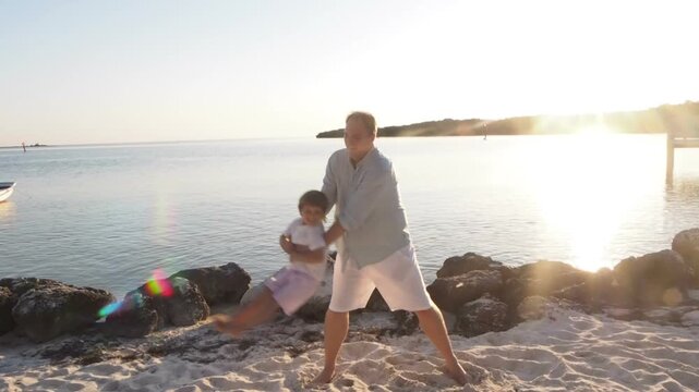 Father Swinging Son on Beach at Sunset, Joyful Family Moment in the Florida Keys