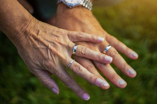 Close-up of elderly couple holding hands and showing wedding rings, symbolizing lasting love, lifelong partnership, and commitment.