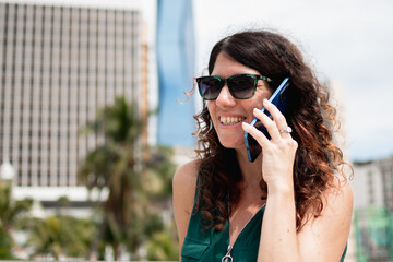 Woman talking on phone, smiling in city outdoors