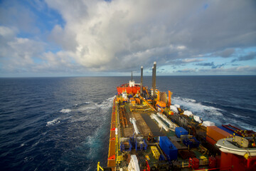 A semi-submersible heavy lift ship underway at sea under dramatic sky