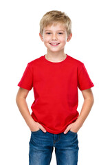 Fototapeta premium A young boy in a red t-shirt and blue jeans stands with hands in pockets, looking cheerful.