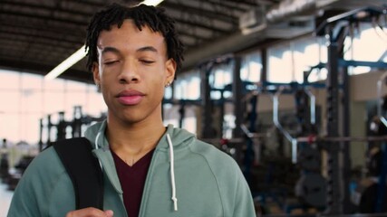 Portrait of a young athlete in a hoodie in a contemporary gym with weights in the background. - Powered by Adobe