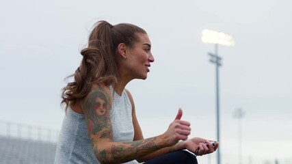 An athletic instructor passionately coaches her students on the field while holding a stopwatch. - Powered by Adobe