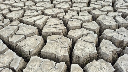 High-angle, close-up shot of deeply cracked, dry earth chunks, showing the dramatic effects of severe drought. A powerful texture symbolizing environmental crisis and lack of water.