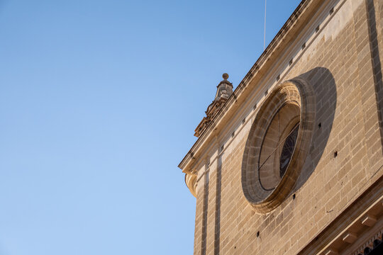 Historic building facade with circular window against clear blue sky on a sunny day. - Powered by Adobe