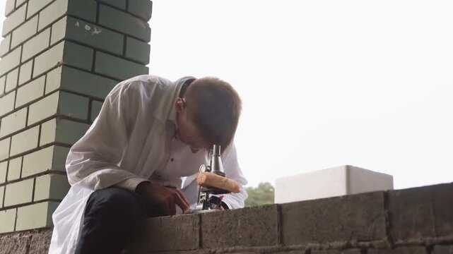 Scientific researcher in white coat sits outdoors carefully examining pastry with microscope after initial magnifying glass observation, reflecting focus, curiosity