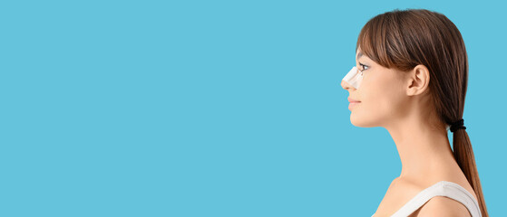 Beautiful young happy woman with bandaged nose on blue background. Plastic surgery concept