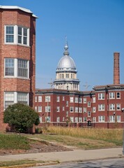 Urban view featuring the Illinois State Capitol dome rising above historic brick apartment buildings under a clear blue sky.