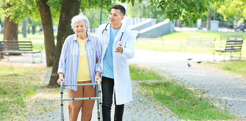 Doctor walking with senior woman in park