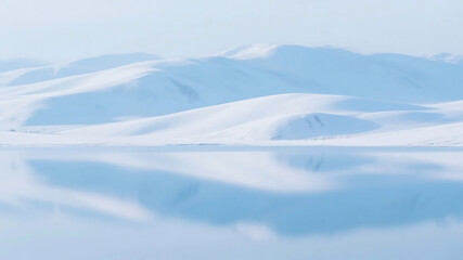 A tranquil scene of snow-covered mountains mirrored perfectly on a calm, icy water surface under a clear sky.