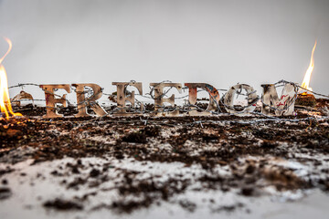 Barbed wire surrounds the word freedom against white seamless background