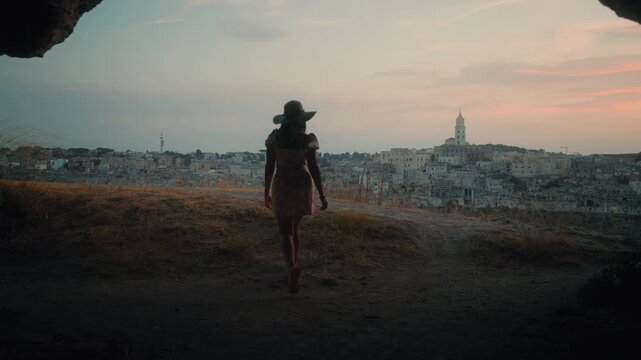 Young Woman Silhouette Standing on Rocky Hillside Overlooking Matera at Golden Hour Sunset Italy