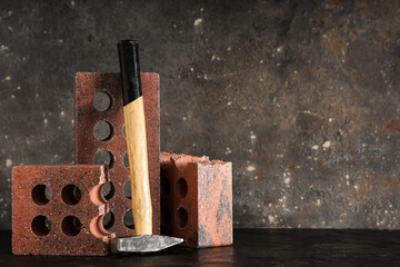 Bricks with hammer on grey grunge background