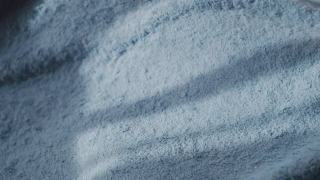 Close up of young girl snuggling under soft blue blanket while wiggling leg, creating gentle folds and textures, cozy indoor atmosphere symbolizing warmth