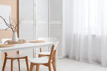 Interior of dining room with table, chairs and folding screen near window