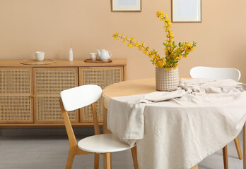 Interior of dining room with chest of drawers, table and chairs near beige wall