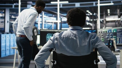 Fototapeta premium Data center programmer in wheelchair entering office uses AI node tree program to minimize system downtime. Server room IT expert in disability uses machine learning visual programming tool, camera A