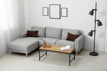 Sofa and coffee table near white brick wall in interior of living room