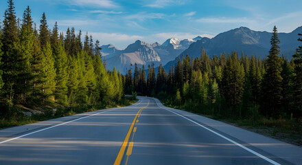 Naklejka premium Scenic mountain road through a vibrant green forest leading to majestic snow-capped peaks under a clear blue sky, evoking journey, travel, and wilderness adventure.