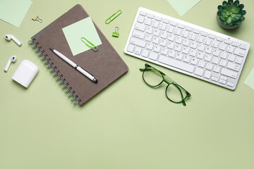 Composition with keyboard, sunglasses, stationery and houseplant on green background